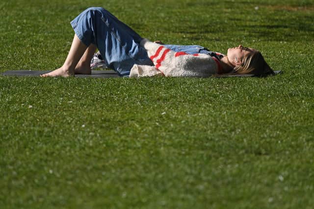 A woman sunbathes on the grass in the Spring sunshine (Photo by DANIEL LEAL-OLIVAS/AFP via Getty Images)