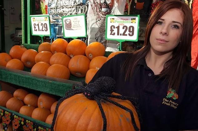 Assistant Jaye Perkins alongside a massive, eye-catching display of pumpkins prepared for Halloween at The Priory Fruit Shop
