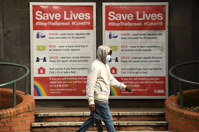 A man wearing a protective face mask passes a board displaying information how to restrict the spread of coronavirus covid-19, in central Nottingham (Photo by OLI SCARFF/AFP via Getty Images)