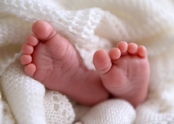 A new born baby's feet are visible peeking out of a shawl