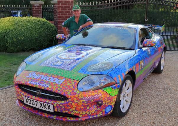 Retired businessman Stuart Dixon with his charity car, adorned with hundreds of stickers.