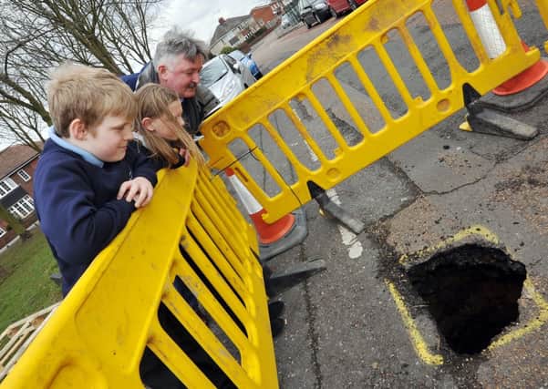 A hole has appeared in the road opposite Sir Edmund Hilary School in Worksop, further investigation revealed it to be an old well.  Pictured inspecting the hole are Coun Glynn Gilfoyle with Sir Edmund Hilary pupils Lewis Smith, 10 and Alys Hoyle, 10 (w130321-4b)