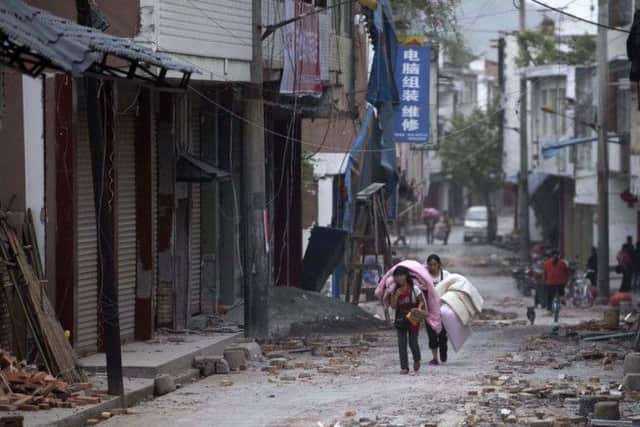 In this photo released by China's Xinhua news agency, people carrying their belongings walk in quake-damaged Gucheng Village, Longmen Township, Lushan County, southwest China's Sichuan Province, Saturday, April 20, 2013. A powerful earthquake struck the steep hills of Sichuan province Saturday, nearly five years after a devastating quake wreaked widespread damage across the region. (AP Photo/Xinhua, Fei Maohua) NO SALES