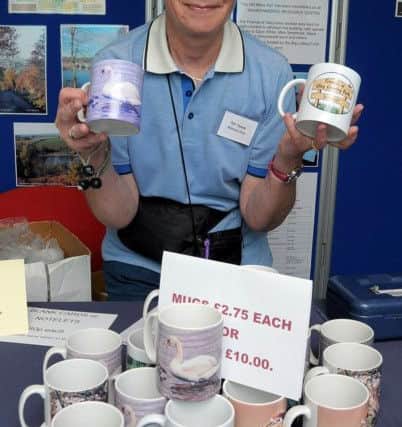 Ulley Country Park's Country Fair, Pat Dyson, Membership Secretary of 'Friends of Ulley Country Park' with printed Mugs for sale. (w130624-2e)