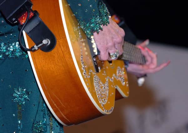 Dolly Parton plays along with her damaged guitar