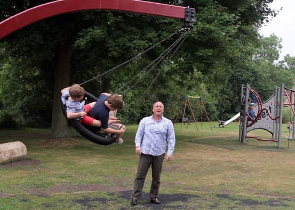 Enjoying one of the new pieces of play equipment are Henry and Finn Edwards watched by dad Tony Edwards.