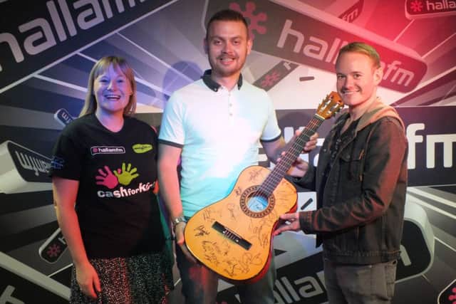 Simon Morykin and Louise Davies of Hallam FM present the signed guitar to Darren Rock