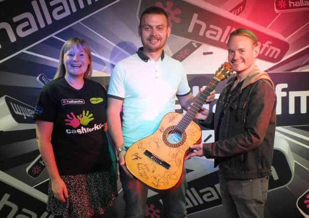 Simon Morykin and Louise Davies of Hallam FM present the signed guitar to Darren Rock