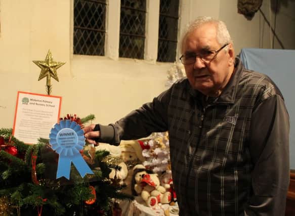 Sid Burgess pins the winners rosette to the winning tree in the Misterton Christmas Tree Festival