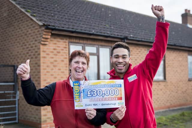Lilian receiving her winning cheque from People's Postcode Lottery Ambassador Danyl Johnson