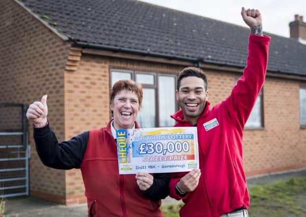 Lilian receiving her winning cheque from People's Postcode Lottery Ambassador Danyl Johnson