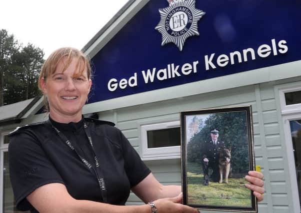 Inspector Annie Reavley, head of the dog section, with a photo of late colleague Ged Walker outside the newly named kennels. Picture: Jason Chadwick.