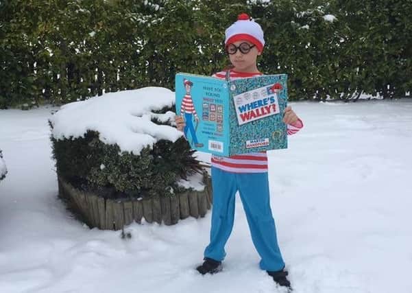 Has Wally been found? This youngster dresses the part as he reads a 'Where's Wally?' book